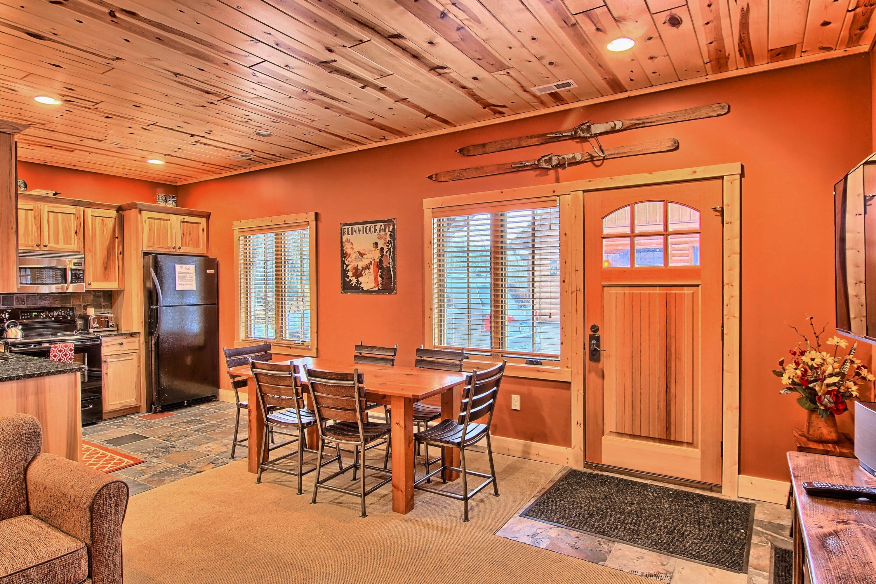 A kitchen with wooden cabinets, a dining table with chairs, and a refrigerator.