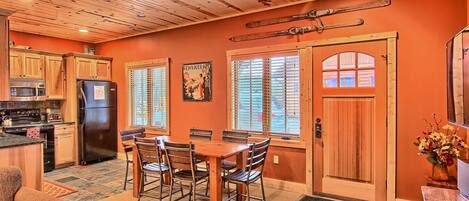 A kitchen with wooden cabinets, a dining table with chairs, and a refrigerator.