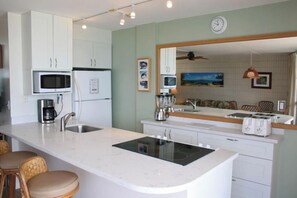 Una cocina moderna con armarios blancos, microondas integrado, estufa y una isla grande con taburetes de bar.