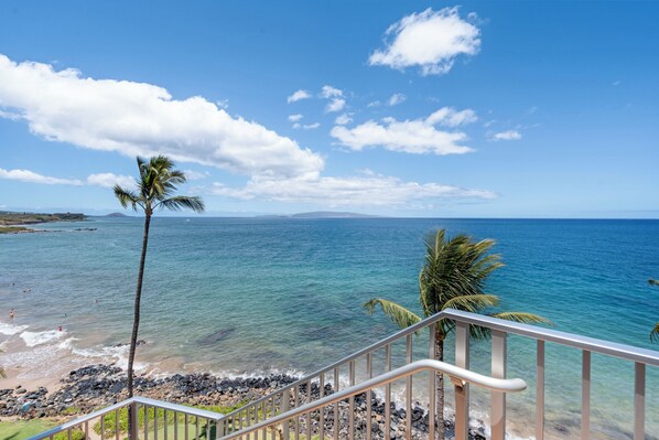 Blick auf die Küste mit blauem Himmel, einem Strand und einer Treppe, die zum Ufer hinabführt.