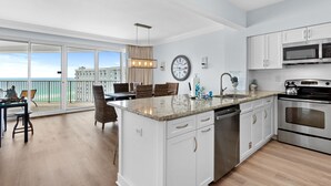 A modern kitchen with white cabinets, a stainless steel oven, and a large island with a sink. - Beachfront 2BR Tops'l Resort! Balcony Beach Views, Tropical Pool, Pickleball (Miramar Beach)