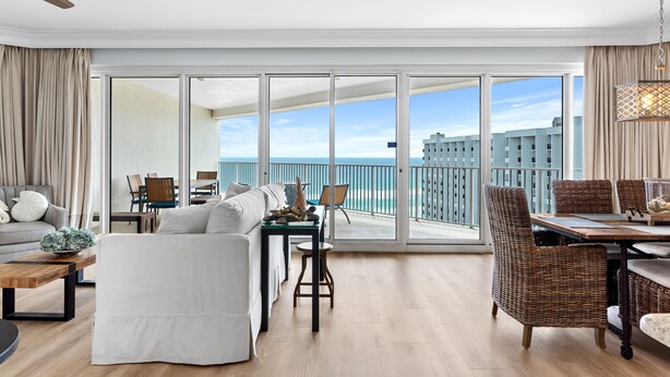 A spacious living room with a large sliding glass door leading to a balcony with a city view. - Beachfront 2BR Tops'l Resort! Balcony Beach Views, Tropical Pool, Pickleball (Miramar Beach)