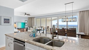 A modern kitchen with a large island, stainless steel appliances, and a view to the outside. - Beachfront 2BR Tops'l Resort! Balcony Beach Views, Tropical Pool, Pickleball (Miramar Beach)