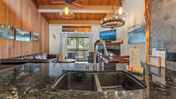 A modern kitchen with a large granite countertop, stainless steel sink, and wooden ceiling. - Updated Interior, 2 Private Decks, Gas Fireplace and Community Pool in Summer! (Kings Beach)