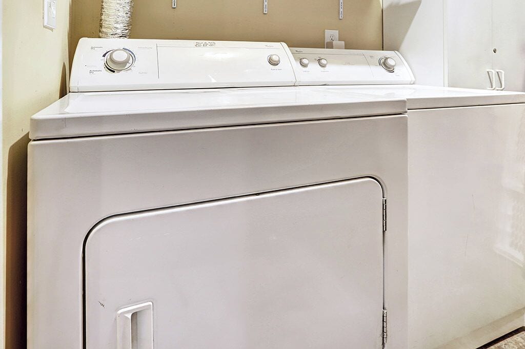 A front view of a white front-loading washer and dryer unit in a laundry room.
