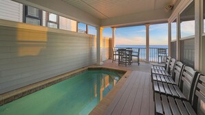 A covered outdoor swimming pool with wooden deck seating and a view of the ocean. - Las Olas - Oceanfront Vacation Home with Private Pool Space & Gulf Views (Miramar Beach)