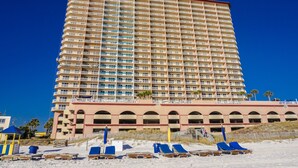 Un hotel alto con varios balcones y una zona de playa con tumbonas.