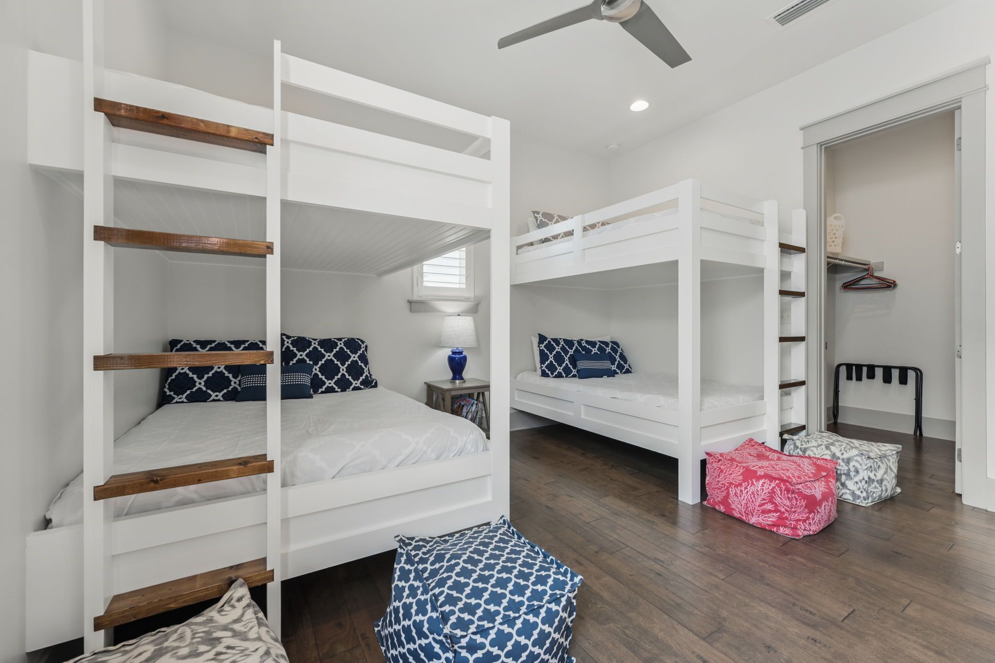 Une chambre avec deux lits superposés, une petite table de chevet avec une lampe et une armoire avec un porte-manteau.