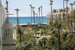 A resort with a pool surrounded by palm trees and a view of the ocean. - Beautiful ocean views, remodeled 2bdrm penthouse condo, C303 North Coast Village (Oceanside)