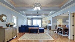 Amplia sala de estar con un sofá azul, una mesa de comedor de madera y un ventilador de techo.