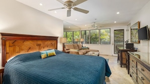 A bedroom with a large bed, a ceiling fan, a sofa, and a TV. - Aloha Condos, Napili Bay Resort, Condo 217, Beach View (Lahaina)