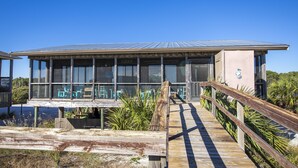 Un bâtiment moderne doté de grandes fenêtres et d’une terrasse en bois donnant sur un espace aménagé pour s’asseoir.