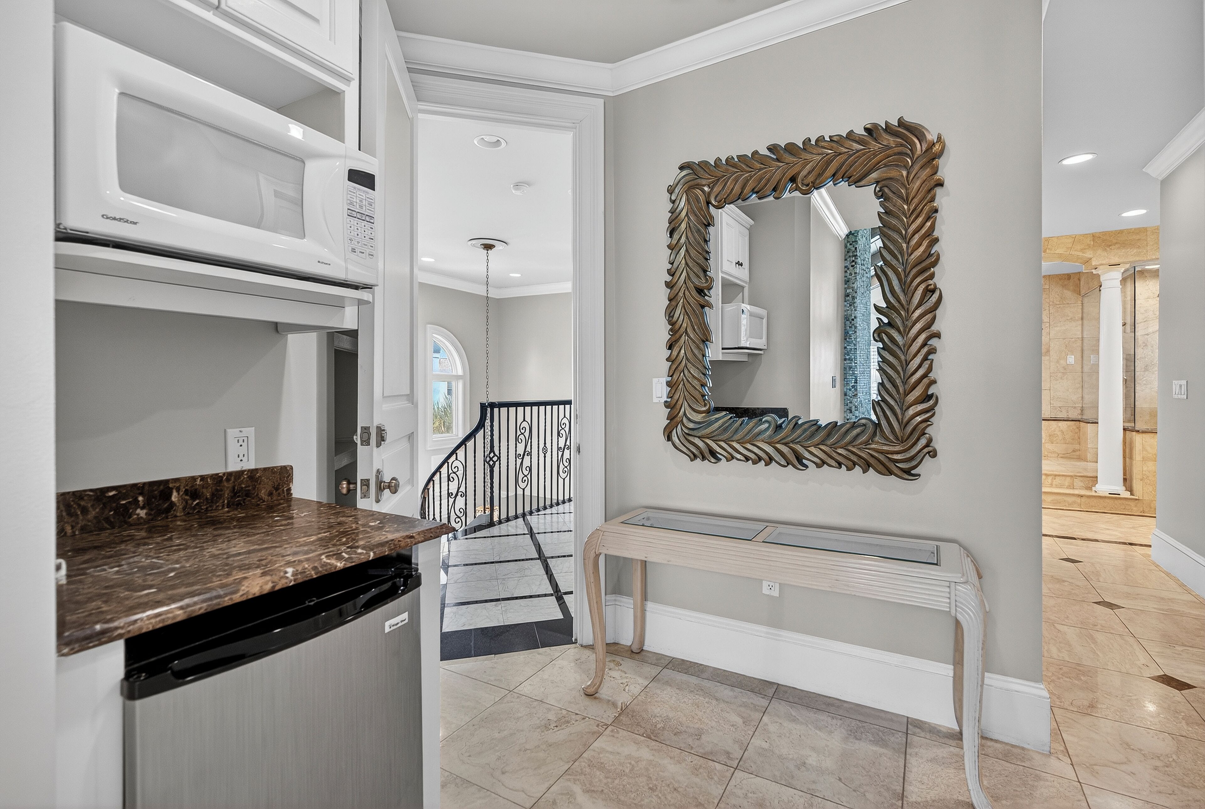 A kitchen with a built-in microwave, a marble countertop, and a dishwasher.