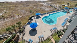 Een resort met een zwembad, ligbedden en uitzicht op het strand.