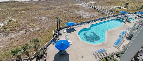 A resort with a pool area, lounge chairs, and a view of the beach.