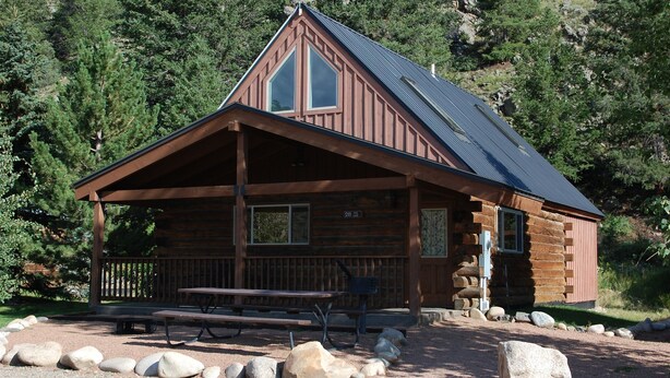 A rustic cabin with a covered porch, a picnic table, and a stone pathway leading to the entrance. - Roomy Taylor Canyon Cabin With Private Fishing Access (Almont)