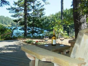 A wooden deck with a bottle and glasses, overlooking a lake and forest. - Munsel Lake Landing with its own dock. (Florence)