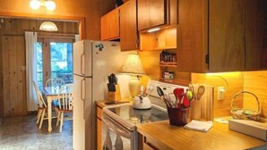 Una cocina compacta con armarios de madera, un refrigerador, una estufa y un comedor con mesa y sillas.