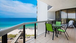 A balcony with a view of the beach and ocean.