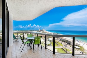 Enjoy the ocean view from this balcony with a table and chairs.