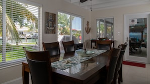 A dining area with a glass-top table, wooden chairs, and a ceiling fan. - *Summer Special $2,775 Week* with a private chilled pool & 75' of dockage (Key Colony Beach)