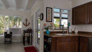 A kitchen with wooden cabinets, a granite countertop, and a window with blinds. - *Summer Special $2,775 Week* with a private chilled pool & 75' of dockage (Key Colony Beach)
