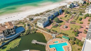 Eine Luftaufnahme eines Resorts mit Strand, Schwimmbad und einer Anlegestelle.