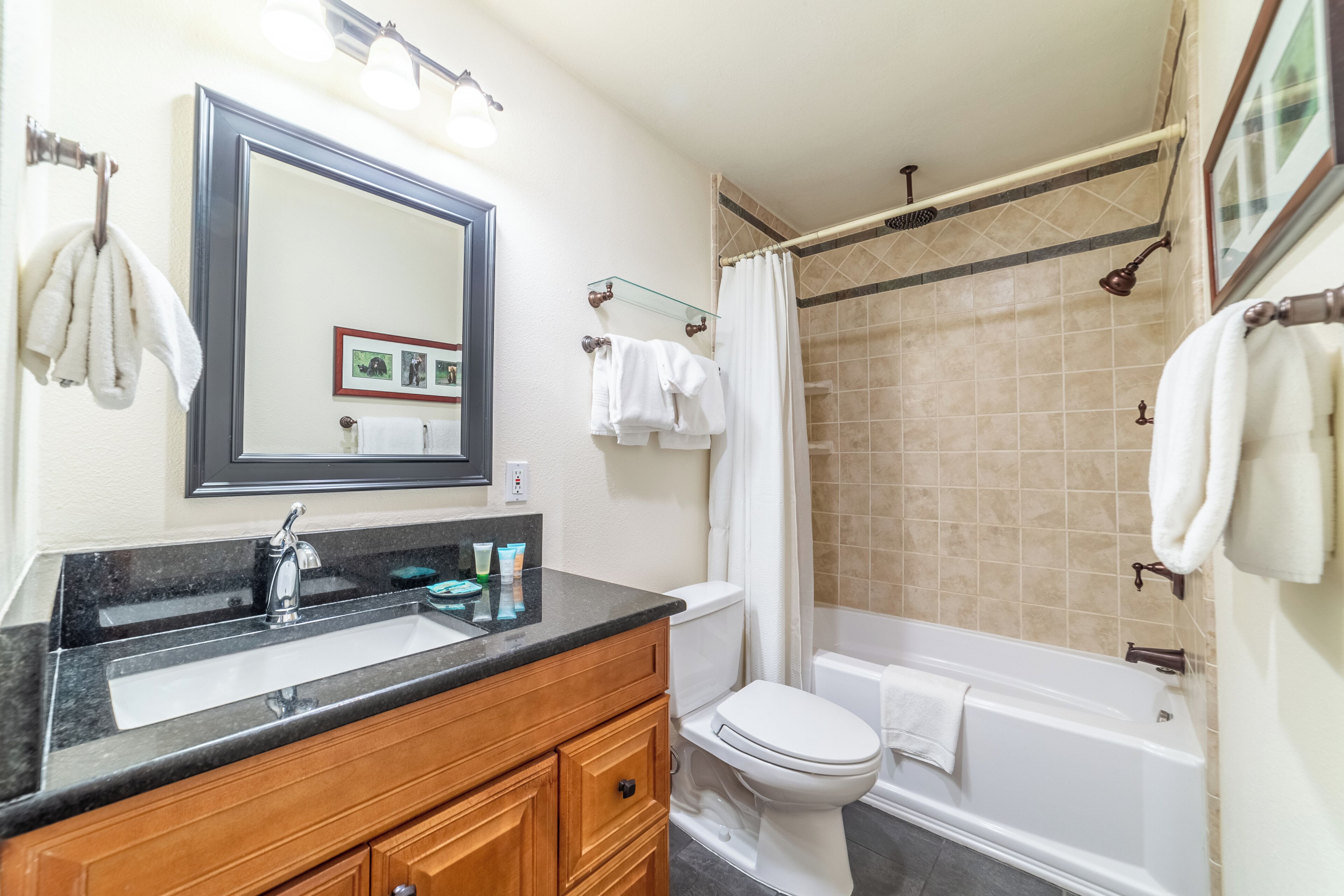 A bathroom with a sink, mirror, toilet, and bathtub.