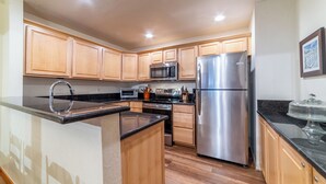A modern kitchen with wooden cabinets, stainless steel appliances, and a black countertop.