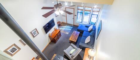 A spacious living room with a blue sofa, wooden coffee table, and a ceiling fan.