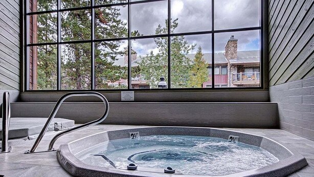 A hot tub with a view of buildings and trees through large windows. - Cimarron 301: Downtown Peak 9 Condo, Wood Fireplace, Pool & Sauna. (Breckenridge)