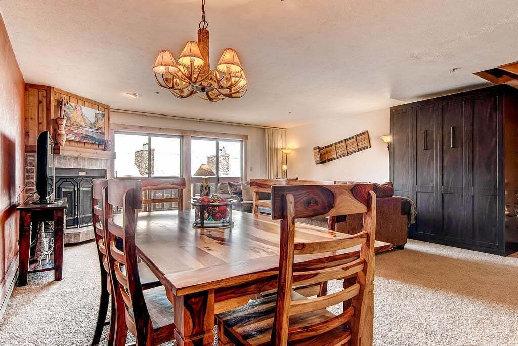 Een ruime eetruimte met een houten tafel en stoelen, een kroonluchter en een open haard.