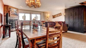 A spacious dining area with a wooden table and chairs, a chandelier, and a fireplace. - Cimarron 301: Downtown Peak 9 Condo, Wood Fireplace, Pool & Sauna. (Breckenridge)