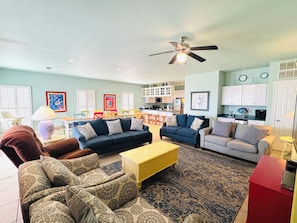 A living room with a sofa, armchairs, a coffee table, and a ceiling fan.