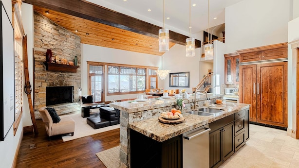 A spacious kitchen with a large island, wooden cabinets, and a stone fireplace. - Luxury Home DV Mid Mountain, Skier Shuttle, Game/Theater Rooms, Hot tub (Deer Valley)