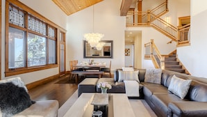 A spacious living room with a large sectional sofa, a dining area, and a staircase leading to an upper level. - Luxury Home DV Mid Mountain, Skier Shuttle, Game/Theater Rooms, Hot tub (Deer Valley)