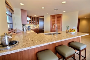 A modern kitchen with granite countertops, stainless steel appliances, and wooden cabinets.