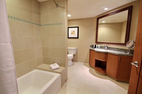 A bathroom with a bathtub, toilet, and wooden vanity with a mirror.