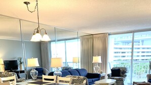 A modern living room with a dining area, large windows, and a view of the city.