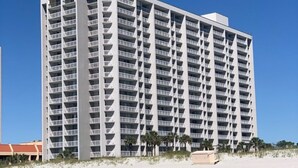 A multi-story hotel with a symmetrical facade, numerous balconies, and a beachfront location.
