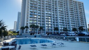 A high-rise hotel with a swimming pool and sun loungers.