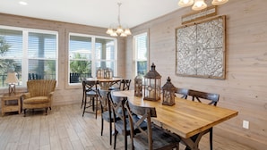 A dining area with a wooden table, chairs, and hanging lanterns. - Pet Friendly | Community Pool | Beach Access (Gulf Shores)