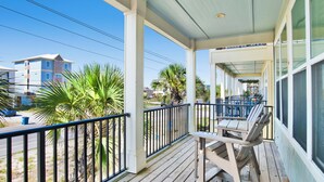 A covered outdoor area with a wooden deck, metal railing, and a table with chairs. - Pet Friendly | Community Pool | Beach Access (Gulf Shores)