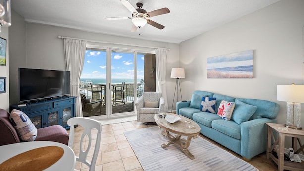A living room with a TV, sofa, coffee table, and a balcony with a view.