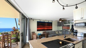 Una cocina moderna con isla, zona de comedor y vista al océano.