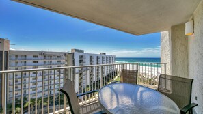 A balcony with a view of the ocean and adjacent buildings.