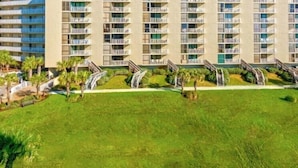 A multi-story hotel with balconies, a central courtyard, and palm trees. - Gulf View! Coastal Chic! Mainsail 288! (Miramar Beach)