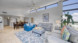 A spacious living room with a high ceiling, a dining area, and a kitchen.