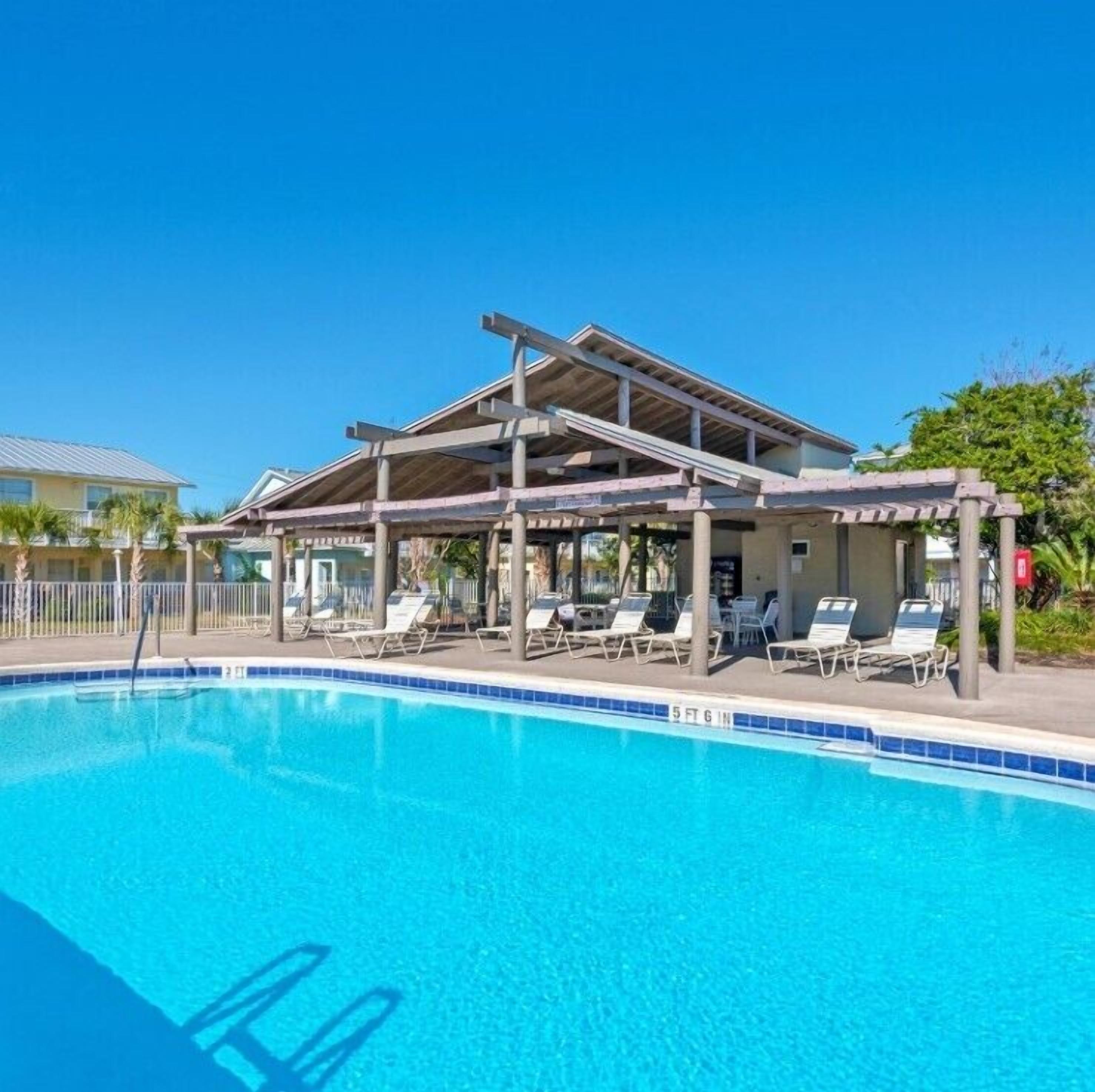 A swimming pool with lounge chairs and a covered area.