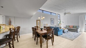 Een ruime woonkamer met een eethoek, een blauwe bank en een plafondventilator.